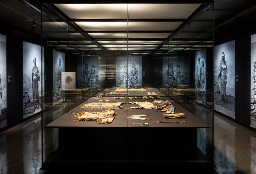 Costumes are displayed on the table, in hues of brown, blue and red.
