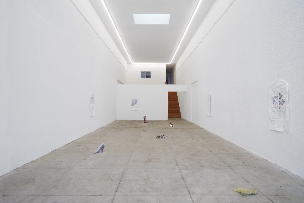 A white installation with shoes on display in hues of brown, black and yellow.