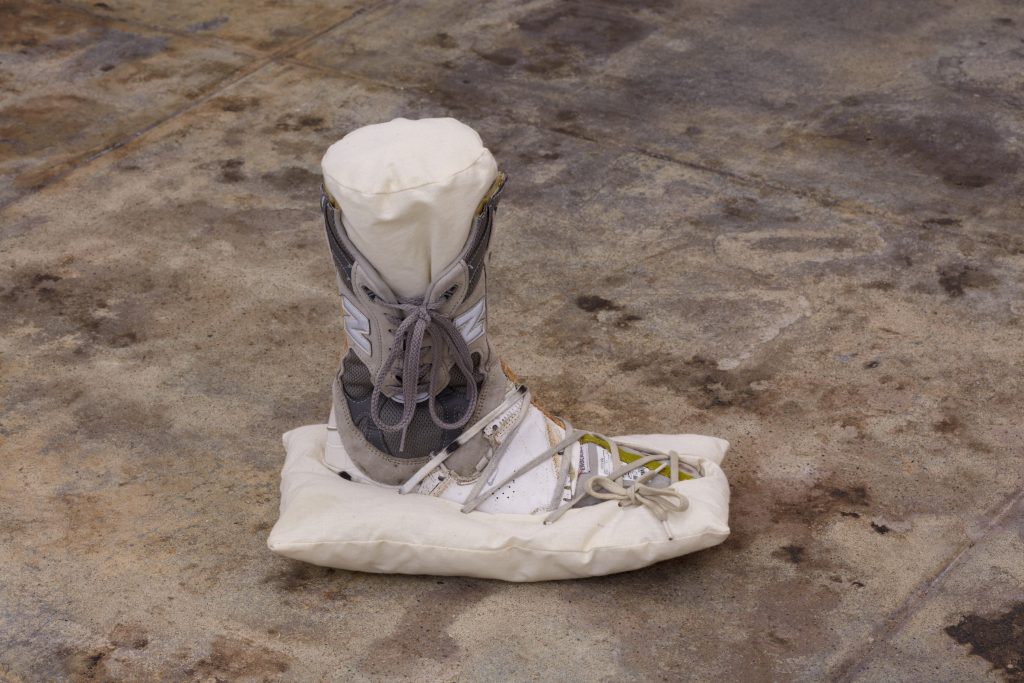 A brown shoe with grey shoelaces wrapped in white tissue.