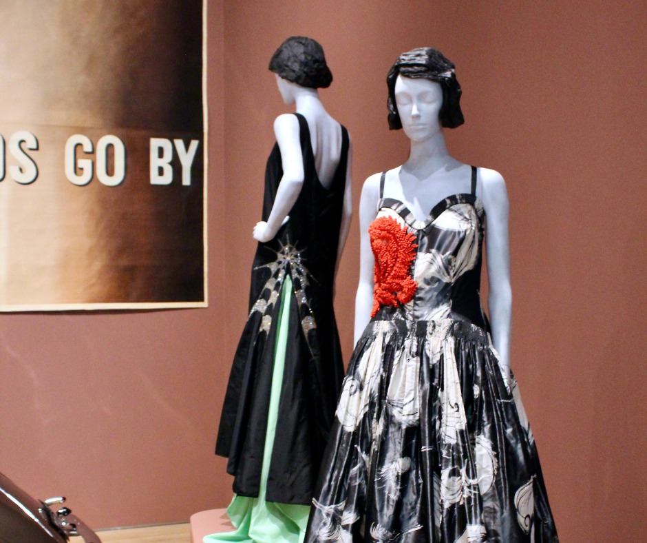 Two black dresses with an accent of red on display.