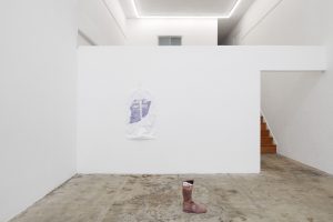 White wall installation with a brown high top boot on display.