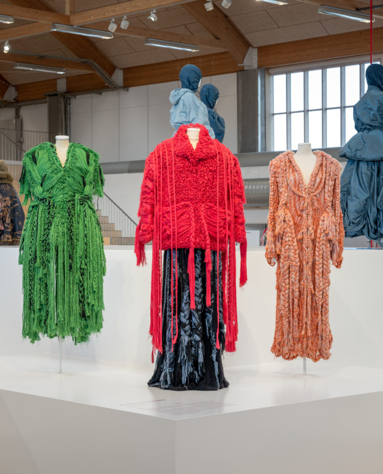 Three outfits in block colours of red, green and orange.