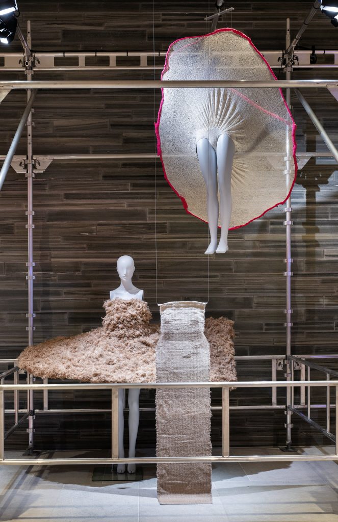 Two mannequins wearing a ruched circular white with red trim.