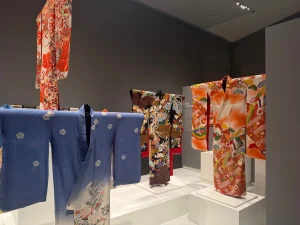 Four patterned kimono on display in hues of blue, orange and brown.
