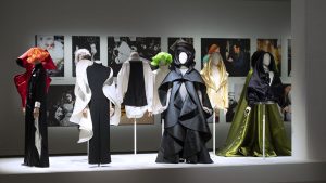 A collection of full length modern gowns in hues of green, black, green and black.