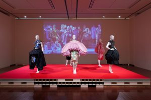 Four mannequins on display with clothing in circular shapes in hues of pink and black.