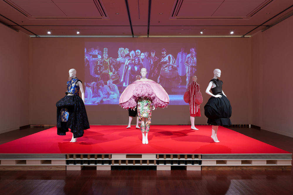 Four mannequins on display with clothing in circular shapes in hues of pink and black.
