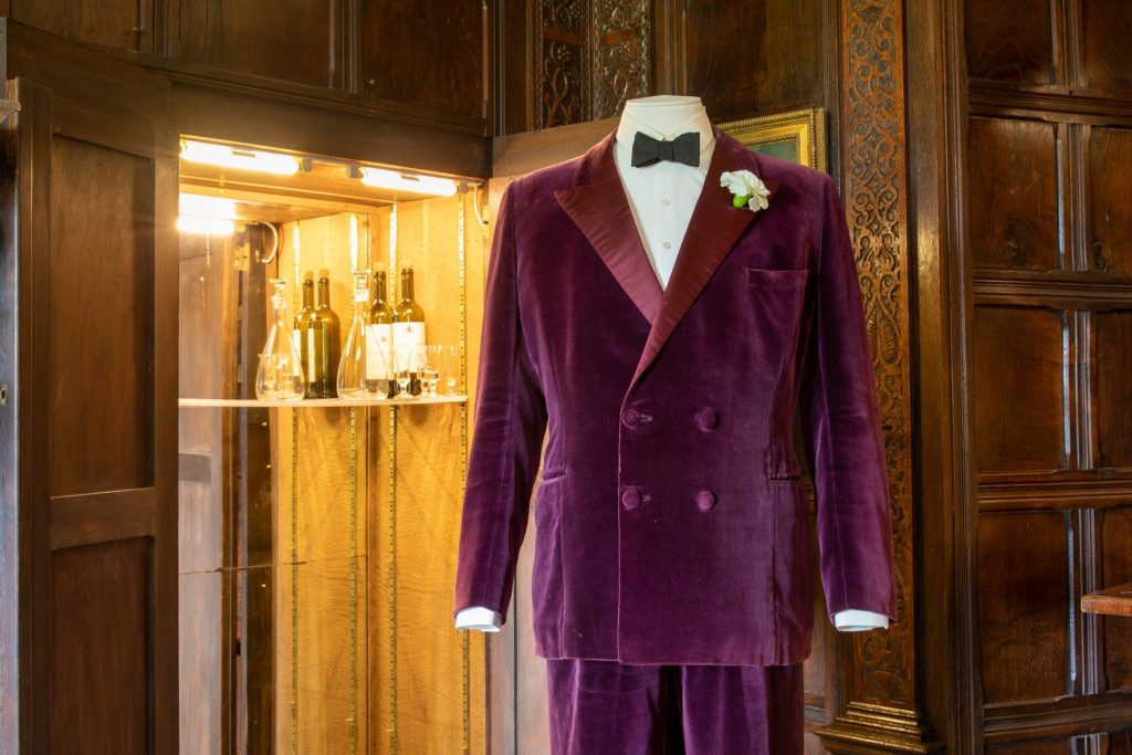purple velvet suit with dickie bow on mannequin. drinks cabinet in background