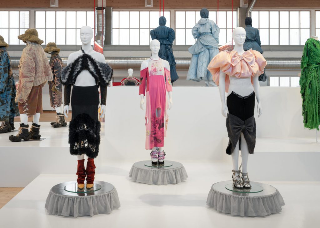 Three outfits in hues of light pink, black, silver and dark pink.
