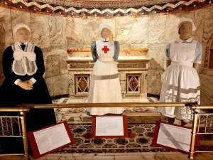 Three mannequins wearing nurses uniform in hues of black, red white and blue.