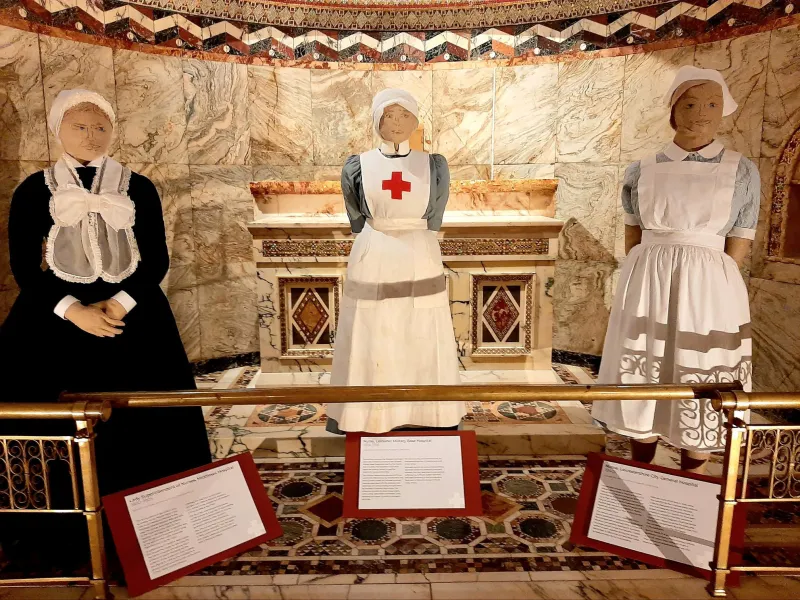 Three mannequins wearing nurses uniform in hues of black, red white and blue.